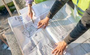 Handen wijzen naar een technisch plan tijdens de voorstudie