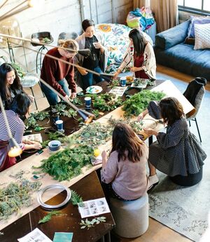 Groep medewerkers werkt tijdens een workshop rond een tafel vol planten en materiaal